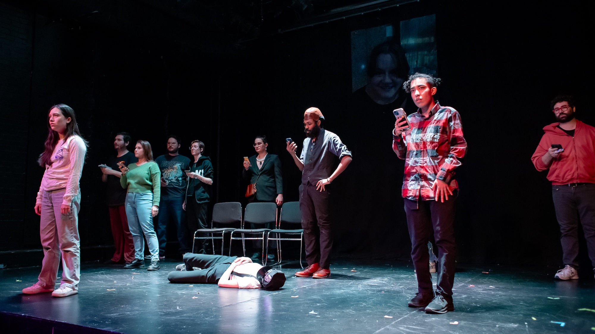 a photo of a group of people on stage looking up from their phones